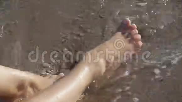 沙滩上晒黑的女性腿沙滩上的海水溅在脚上视频的预览图