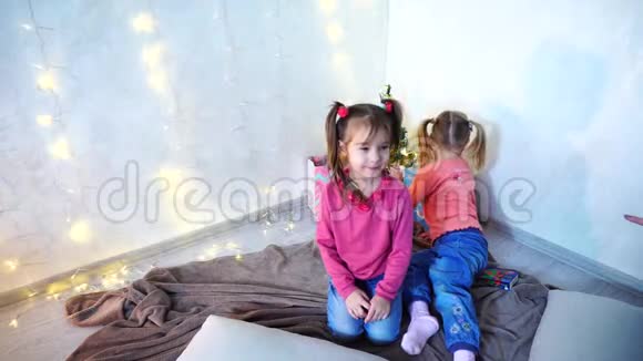 少女们的孩子们在墙上戴着花环坐在地板上地毯上嬉笑打闹视频的预览图