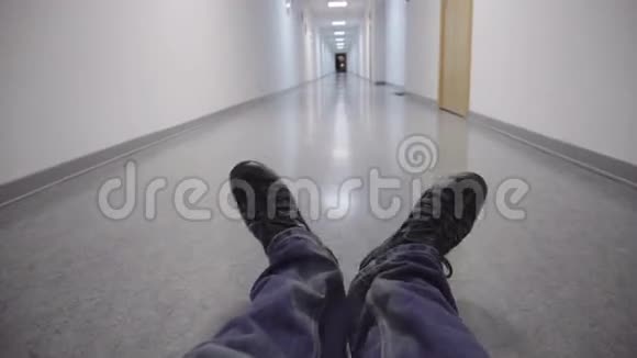 有趣的双脚坐在一条长长的白色走廊的地板上视频的预览图
