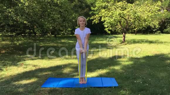 漂亮的学龄女孩在公园里用橡皮筋和垫子在户外做运动健康的生活方式视频的预览图