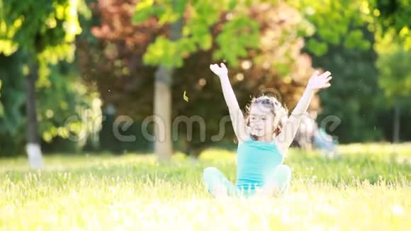可爱的小女孩坐在草地上夏天在公园里玩视频的预览图