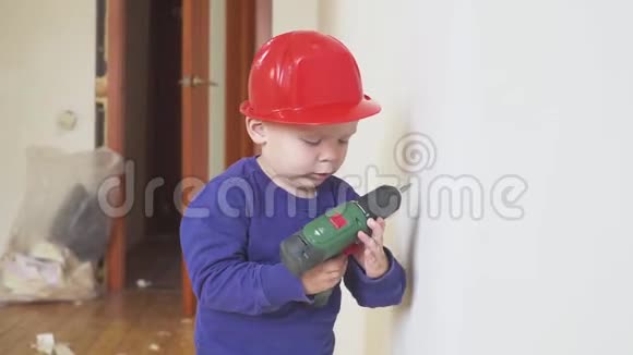 年轻可爱的建筑男孩穿着制服戴着安全帽或头盔在电动螺丝刀的背景下视频的预览图