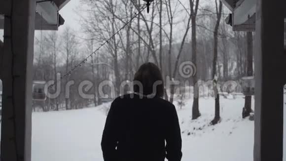 穿着黑色毛衣的年轻人走到冬天的森林后景视频的预览图