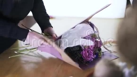 一位年轻的花店员工把一束花包在桌子上视频的预览图