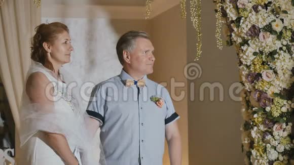 快乐的成年夫妻在花拱下结婚视频的预览图