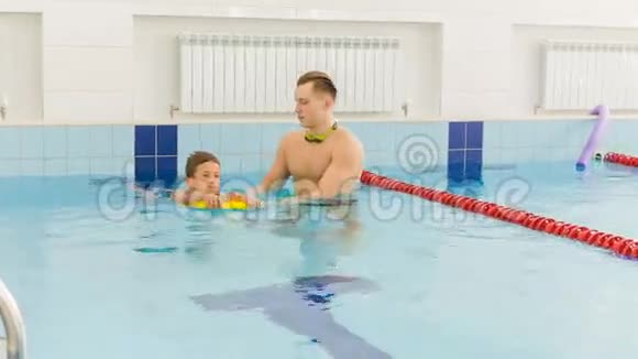 老师和孩子在游泳池里做运动教练教男孩游泳视频的预览图