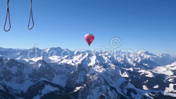 一个热气球在雪上飞行覆盖了瑞士中部高山高峰视频的预览图
