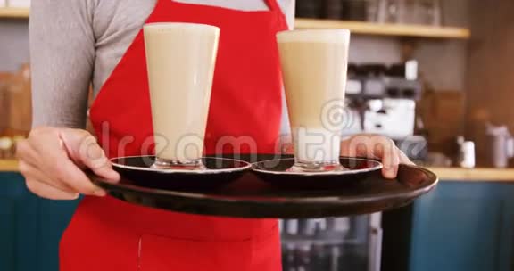 微笑的女服务员在咖啡馆里端着两杯冷咖啡视频的预览图