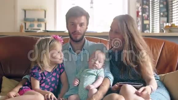 四口之家正坐在沙发上聊天父亲抱着他新生的儿子4k视频的预览图