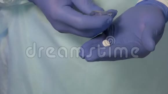 戴医用手套的男医生的手将药片从包装中取出必须将药片送到病人手中视频的预览图