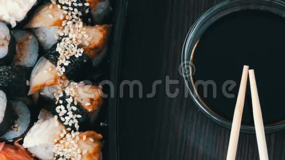 镜头向上移动在酱油和中国竹签旁边的黑色木制背景上摆放时尚寿司视频的预览图