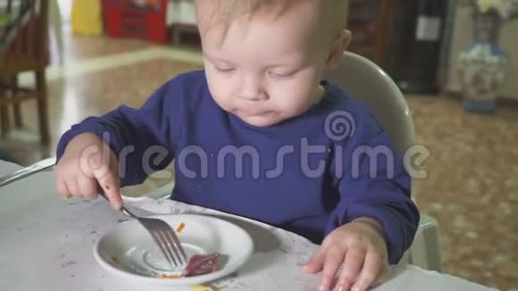 那孩子正在餐馆吃午饭手里拿着勺子和叉子视频的预览图