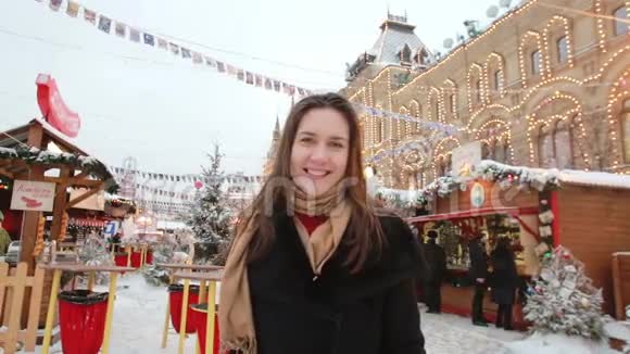 微笑的女孩亲吻站在莫斯科红场的冬天在国家百货商店前视频的预览图