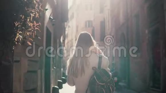 早晨在欧洲城市街道上散步的年轻女子的后视图一个女孩独自在老城探险四处张望视频的预览图