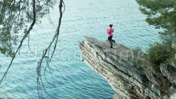 瑜伽教练令人惊叹的悬崖景色和一个正在海上锻炼的女人在高高的窗台上视频的预览图
