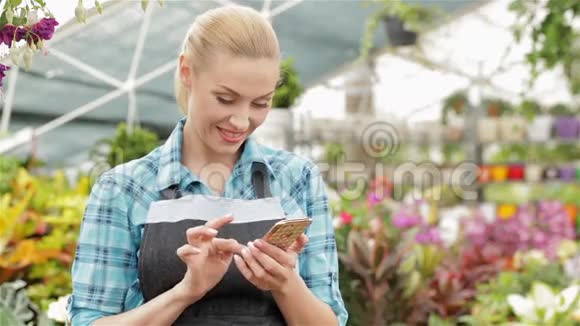 女性花店在花园中心使用智能手机视频的预览图