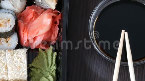 镜头向上移动在酱油和中国竹签旁边的黑色木制背景上摆放时尚寿司视频的预览图