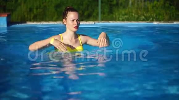 年轻的美女在游泳池里游泳微笑着美丽的女人视频的预览图