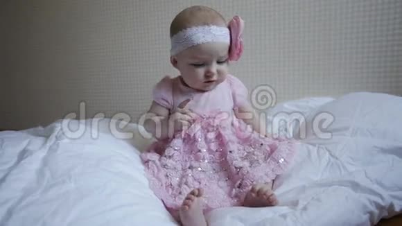 穿着粉红色裙子的小女孩坐在床上视频的预览图