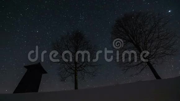 夜空中的星星在木制钟楼上移动冬天树木的轮廓天文时间流逝多莉拍摄视频的预览图