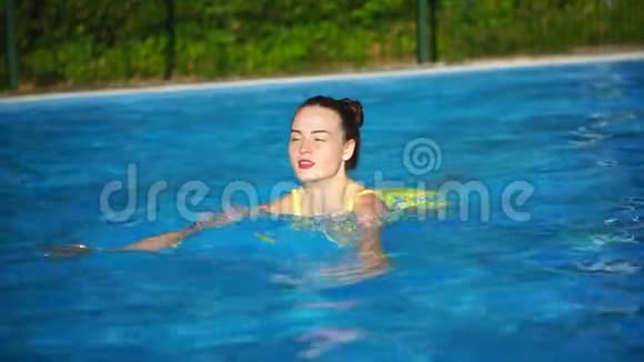 年轻的美女在游泳池里游泳微笑着美丽的女人视频的预览图