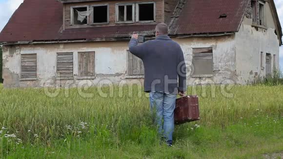 一名男子提着手提箱在废弃建筑附近的平板电脑上拍照视频的预览图