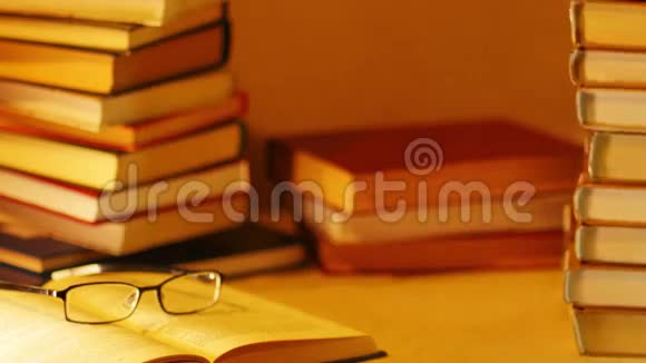 桌子上成堆的书在打开的带眼镜的书旁边出现了畅销的题词停止运动视频的预览图