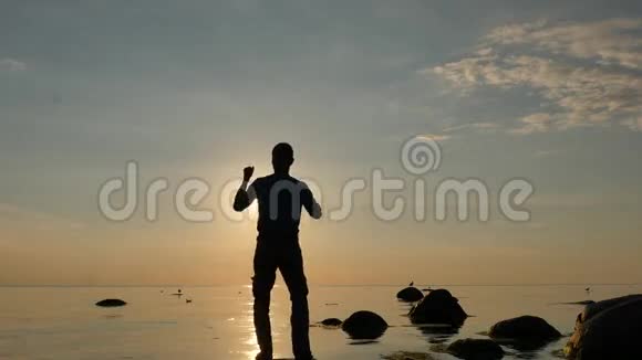 日落时在海上跳舞的男人70的慢动作视频的预览图