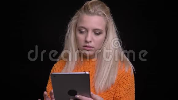 年轻漂亮的白种人女性在平板电脑上浏览的特写镜头背景与黑色隔离视频的预览图