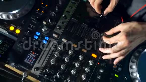在夜总会使用搅拌机和转盘来特写DJ的手视频的预览图