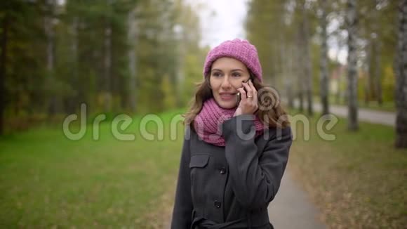 秋日散步时一位年轻的美女在黄红叶背景下用手机聊天视频的预览图