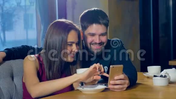 年轻男女在咖啡馆使用新的应用程序智能手机微笑快乐随意的青少年视频的预览图