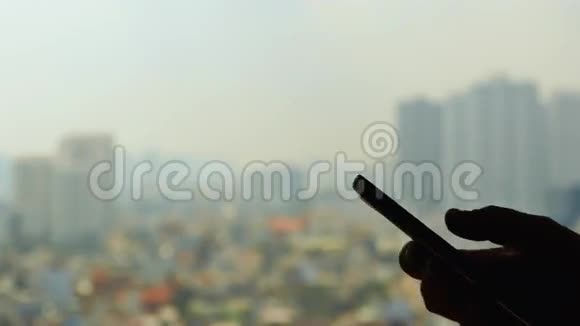 男人从窗户对着城市的背景拨电话视频的预览图