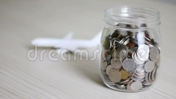 钱币掉进玻璃罐里飞机模糊背后的比喻是为旅行和交通理念省钱视频的预览图