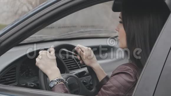 一幅美丽的年轻女子坐在车轮后面的画像视频的预览图