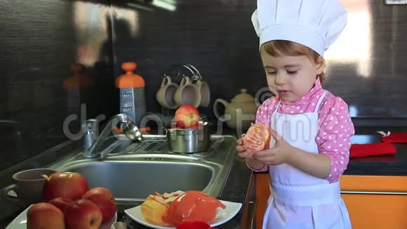 打扮成厨师的可爱的小宝宝帮助妈妈清洗橘子视频的预览图