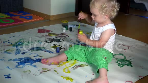 可爱的女婴在家里的地板上用白纸画画视频的预览图
