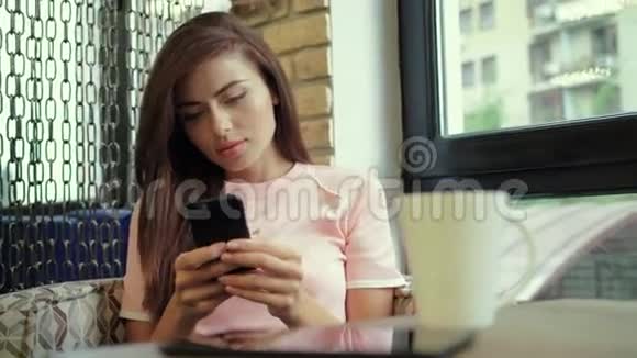 在咖啡馆工作年轻漂亮的长发女人坐在桌子旁在室内使用电话视频的预览图