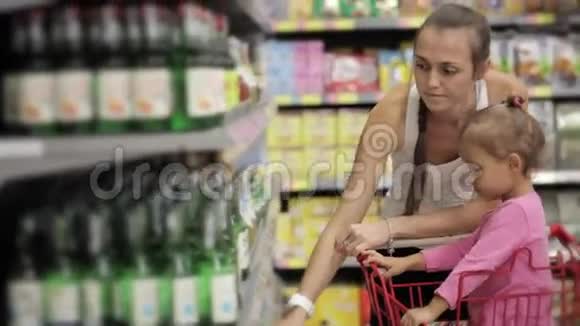漂亮的年轻女人带着宝贝女儿在超市挑选饮料视频的预览图