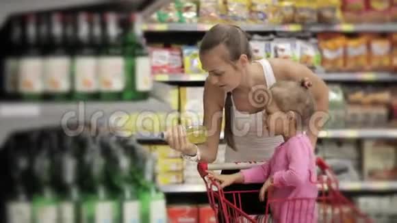 漂亮的年轻女人带着宝贝女儿在超市挑选饮料视频的预览图