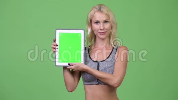 年轻快乐的美女展示数字平板电脑准备健身房视频的预览图