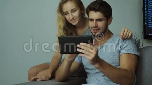 幸福的年轻夫妇用平板电脑穿着砖墙背景上的时髦衬衫视频的预览图