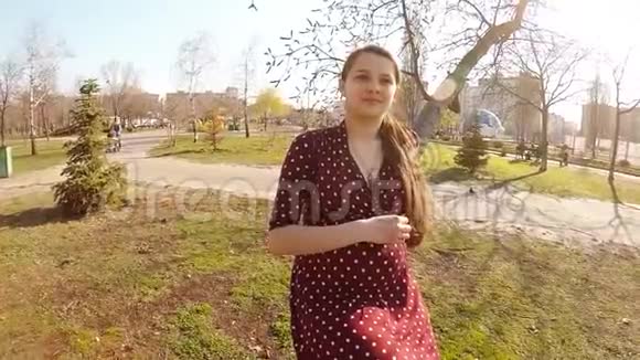 春天公园里一个穿着连衣裙的孕妇正在树下抚摸着肚子视频的预览图