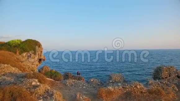两个人站在海岸的岩石上视频的预览图