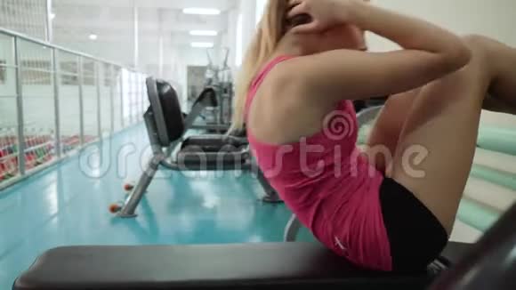 这个女孩在腹部肌肉上做运动抬起躺在长椅上的上身抬起后备箱视频的预览图