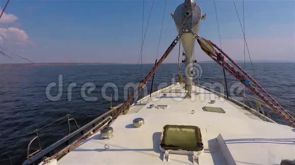 从甲板向前看白色钢制游艇在深蓝色的水上行驶在没有云彩的蓝天下行驶视频的预览图