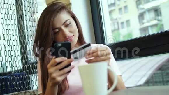 美丽的女子网上银行使用智能手机在线购物信用卡视频的预览图