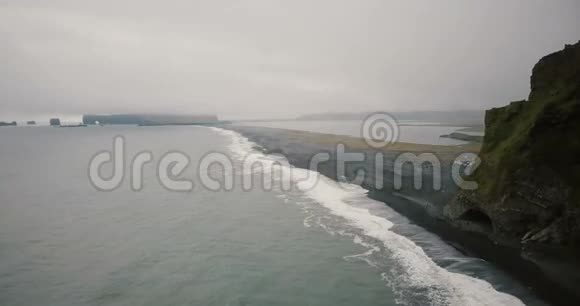 鸟瞰冰岛黑火山海滩和靠近大海的山脉成群的游客在岸上散步视频的预览图