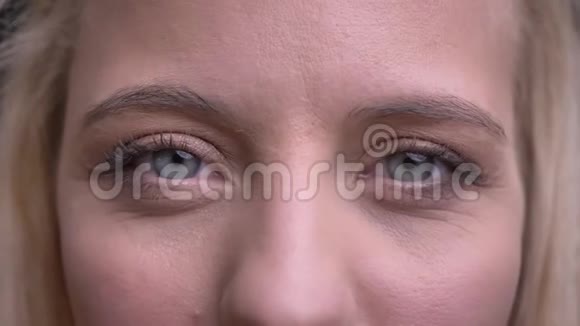年轻美丽的白种人女性的特写镜头灰色的眼睛直视镜头带着微笑的表情视频的预览图