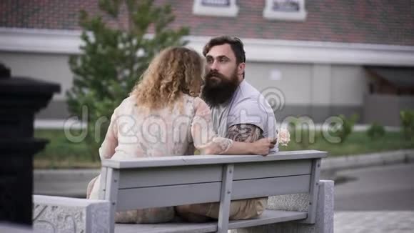 在阳光明媚的天气里可爱的一对夫妇坐在白色的长凳上视频的预览图